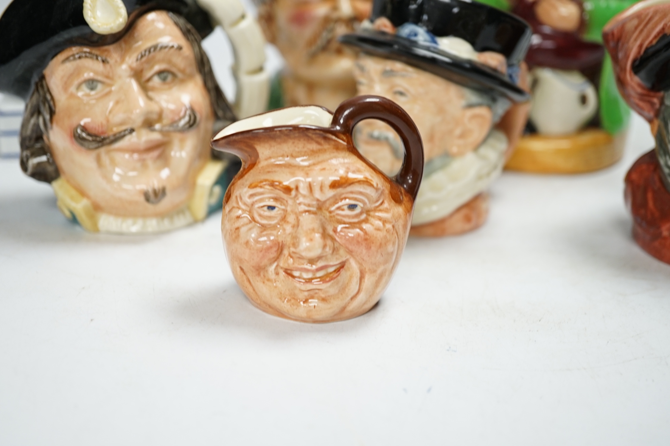 An F. Bridges Phrenology head inkstand, four Royal Doulton Toby jugs, two others, a phrenology bust and a framed pietra dura panel, tallest 17cm. Condition - poor to good, bust broken and re-glued